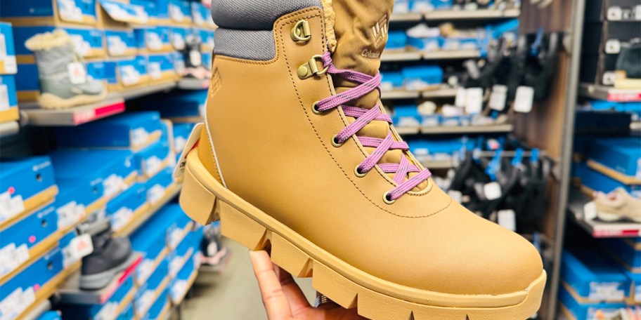 hand holding tan boot with purple shoelaces