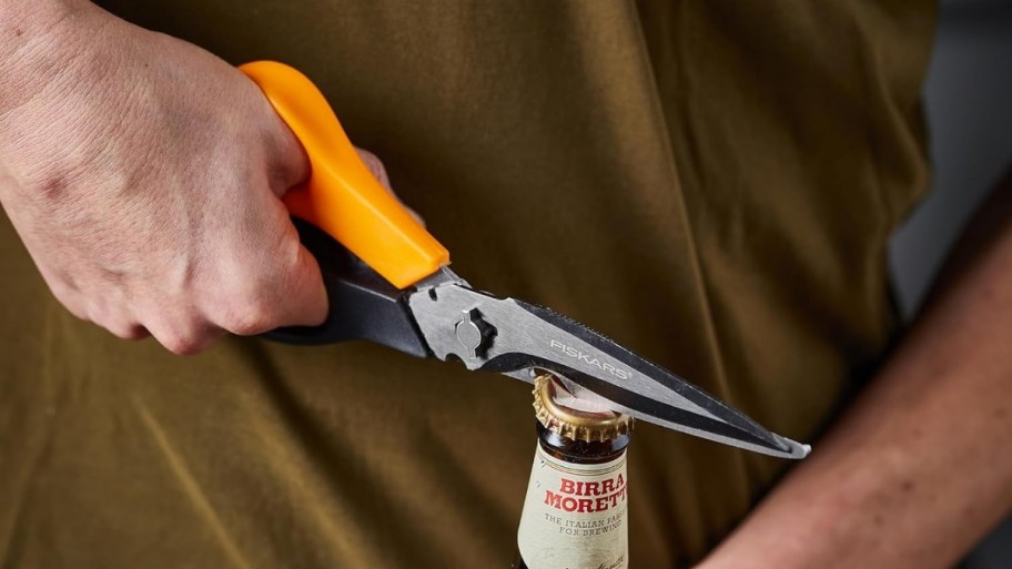 a man opening a bottle of beer with a pair of garden shears