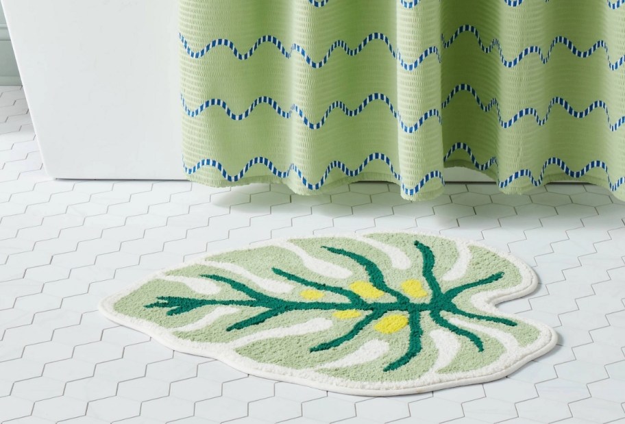 a leaf shaped bathroom rug next to a bathtub