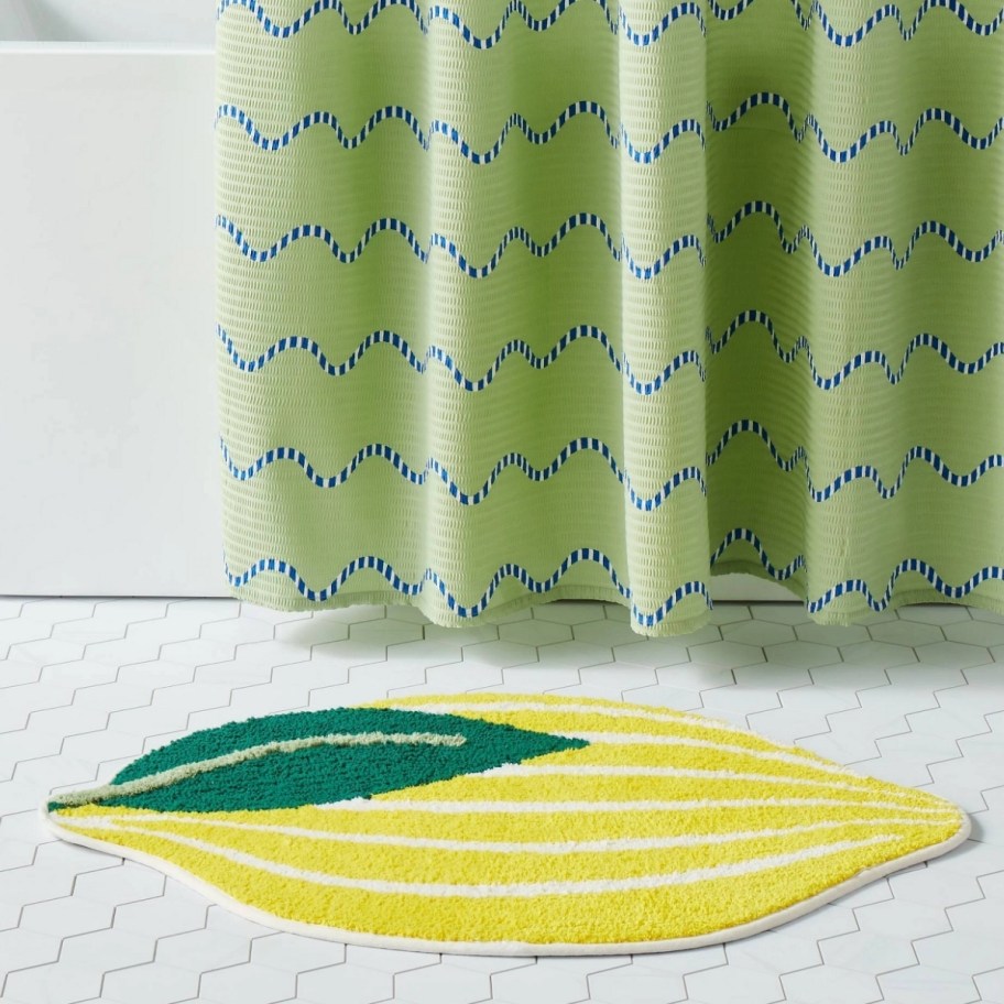 a lemon shaped bathroom rug next to a bath tub