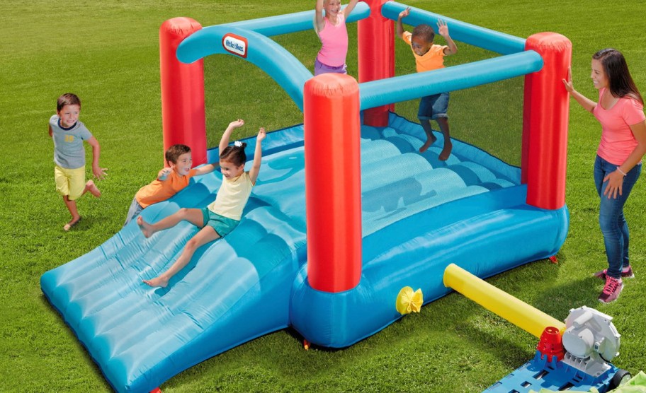 kids playing on blue and red inflatable bounce house outdoors 