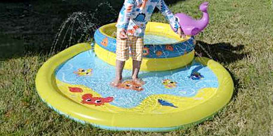 kid standing in little tikes pool outside 