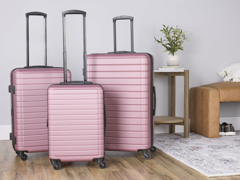 A pink luggage set in a living room.