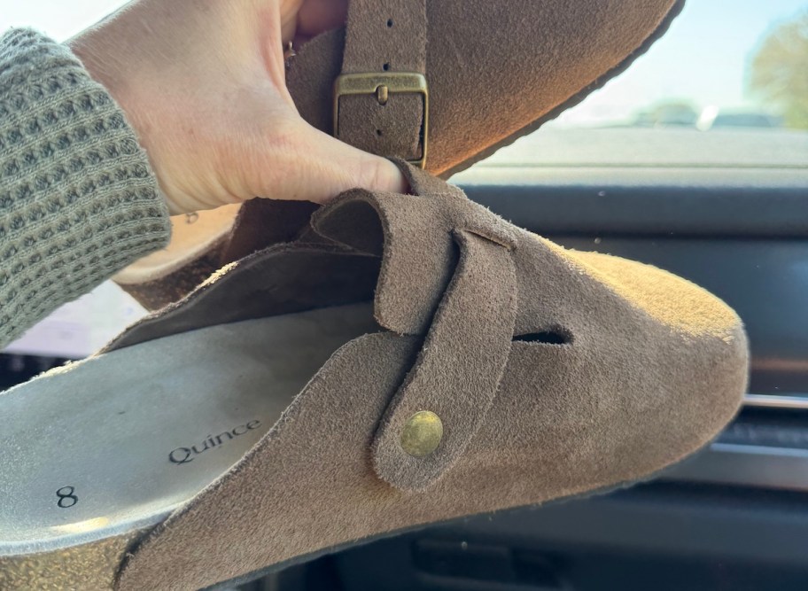 hand holding a pair of suede brown tan quince clogs
