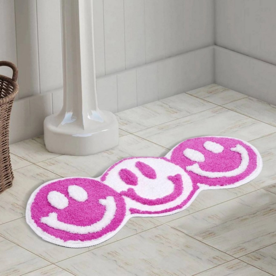 a smiley face shaped bathroom rug next to a bathtub