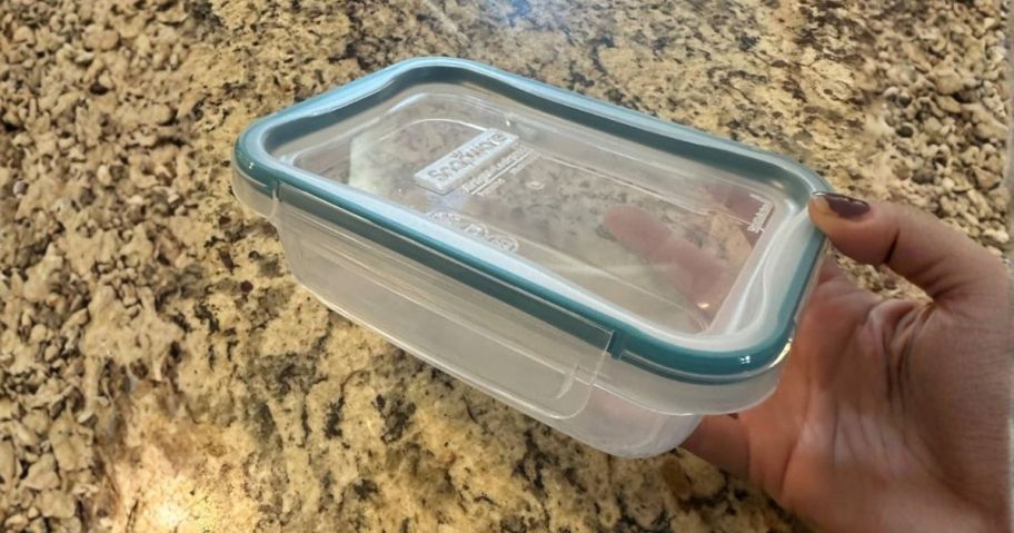 hand holding snapware container in kitchen