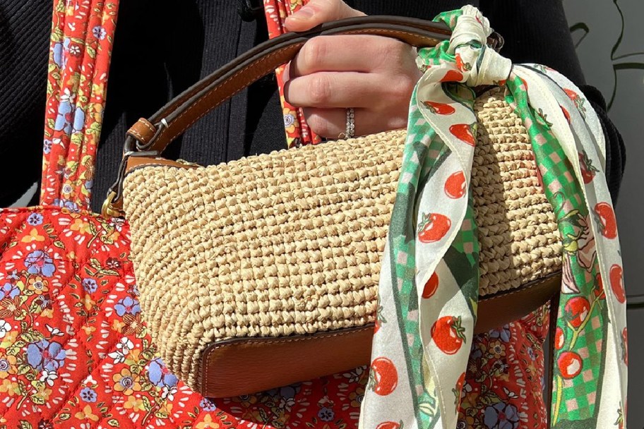 hand holding straw purse with green stain wrap tied around it