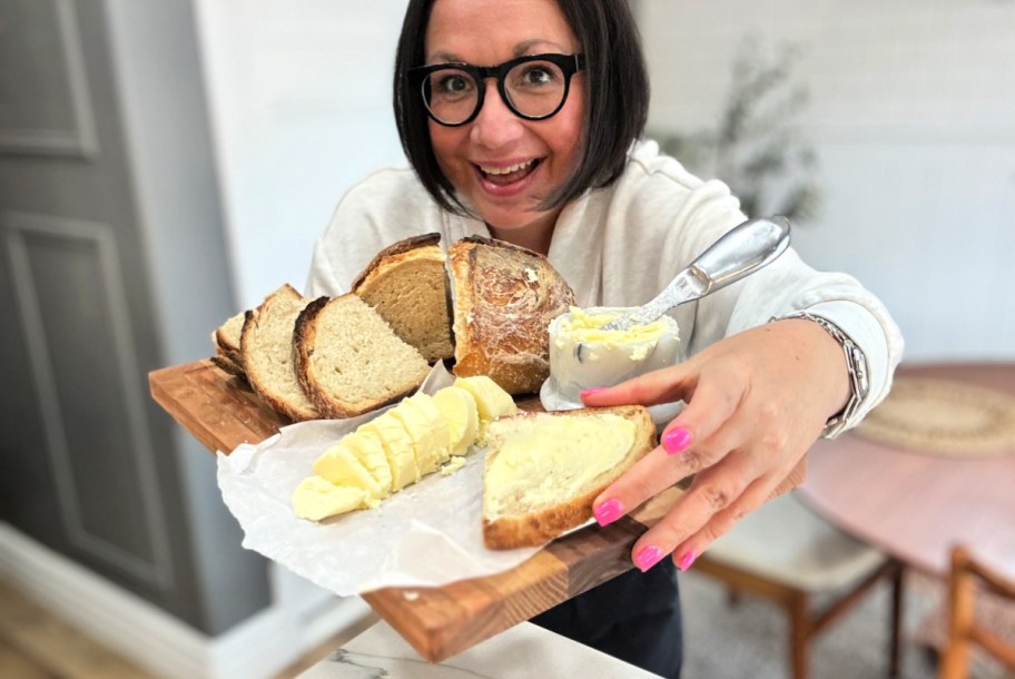 woman holding a wood tray with homemade butter and bread 