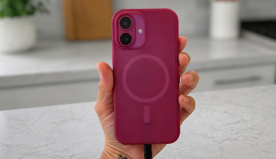 a hand holding a phone in a dark pink case