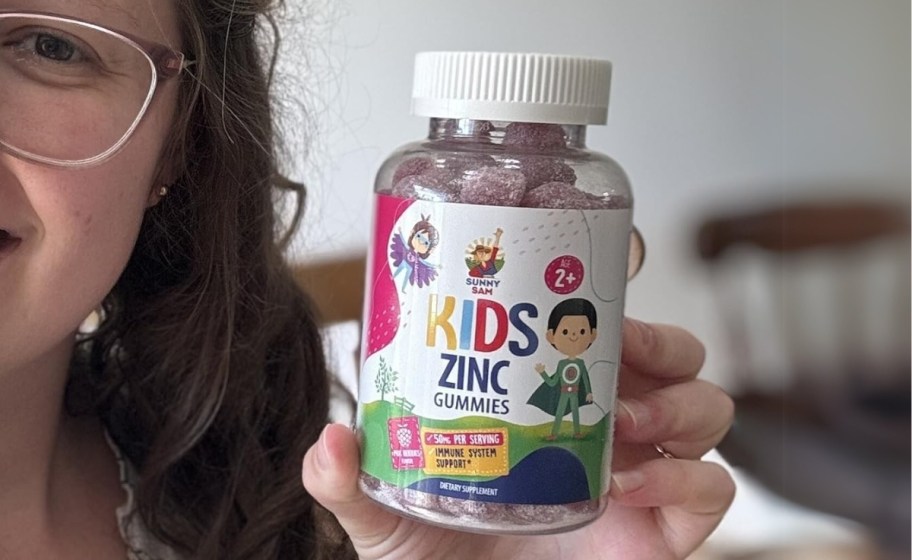 a girl holding a bottle of sunny sam zinc gummies