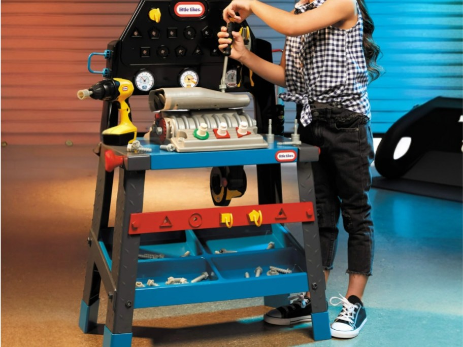little boy using toy tools on a Little Tikes wood shop playset