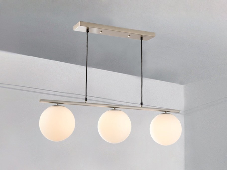a pendant light with 3 frosted glass globes hanging from a ceiling