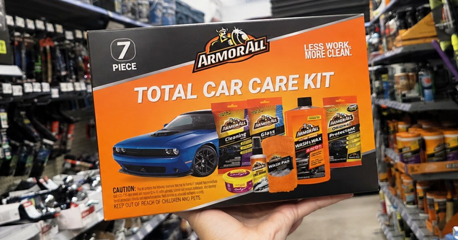 hand holding up an orange Armor All 7-Piece Car Care Kit box in store aisle