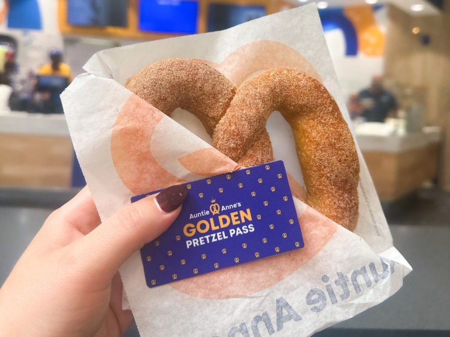 holding a pretzel and a golden pretzel pass from Auntie Anne's