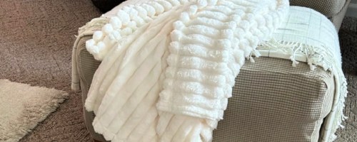White ribbed throw blanket on top of beige ottoman