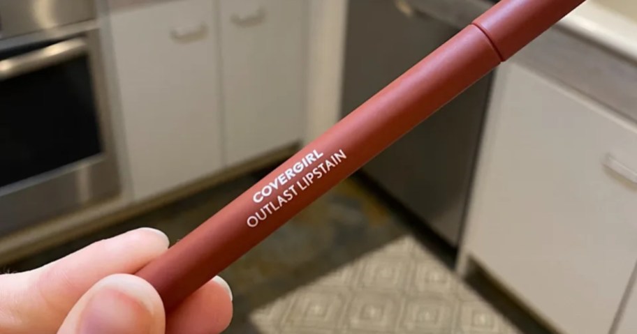 woman holding tube of covergirl outlast lipstain