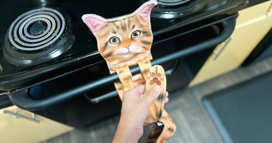 Cat Shaped Hand Towel on a stove handle being touched by a person