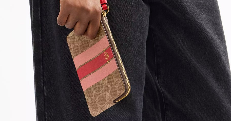 woman holding a striped coach wristlet