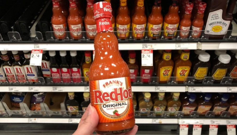 A person holding a bottle of Frank's RedHot in a store