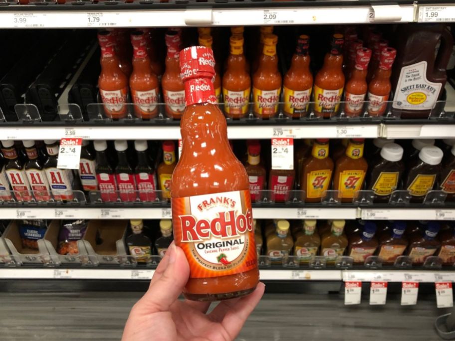 A person holding a bottle of Frank's RedHot in a store