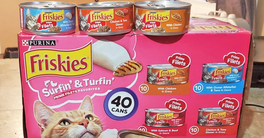 pink box of Friskies Surfin’ and Turfin’ Prime Filets cat food with 3 cans on top of it