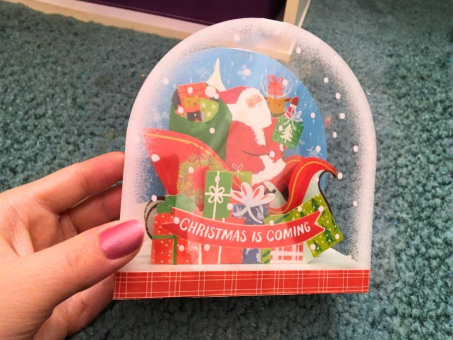 hand holding a pop up snow globe christmas card