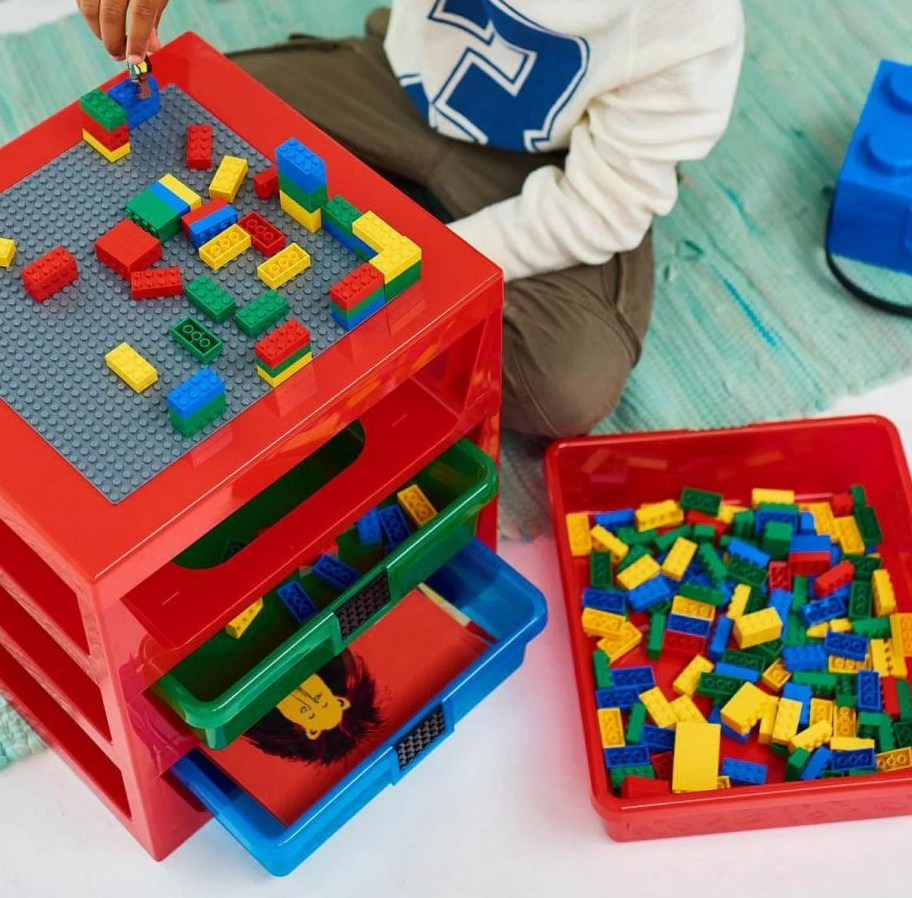 boy building legos on top of a storage box