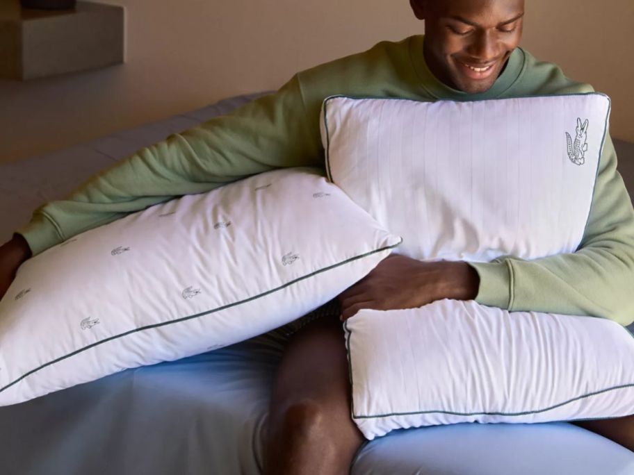 man holding two Lacoste Home All Over Crocs Cotton Firm Density Pillows