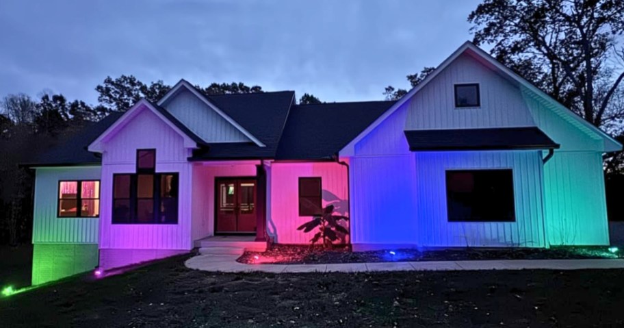 a house lit up in multiple colors from solar powered outdoor lights