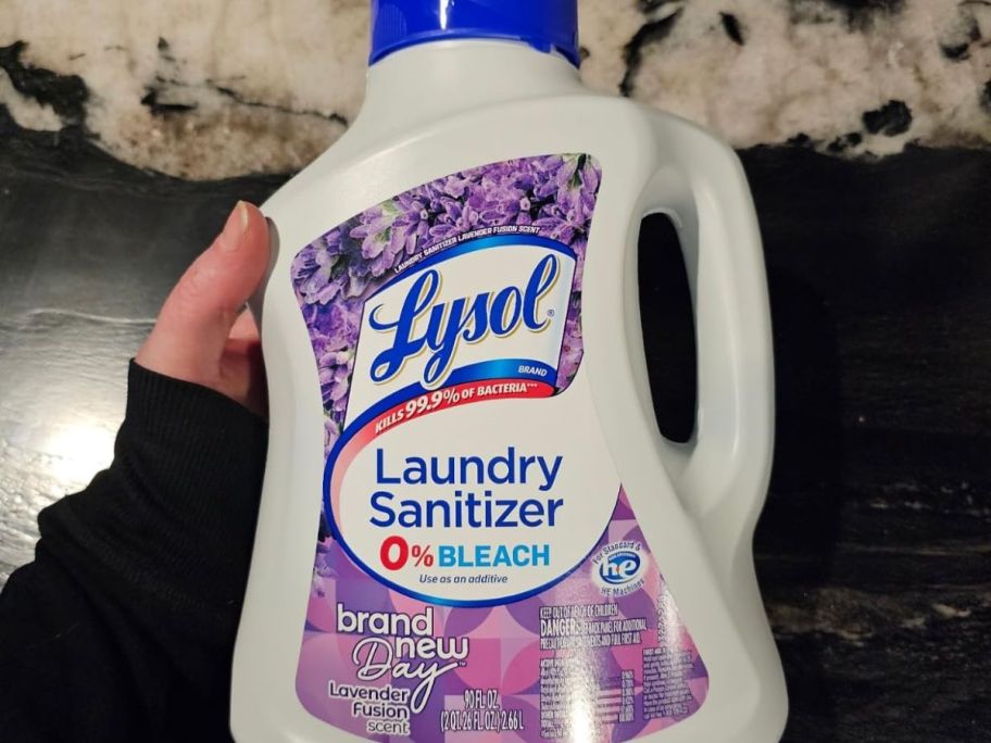 Hand holding a bottle of Lysol Lavender Fusion Laundry Sanitizer 
