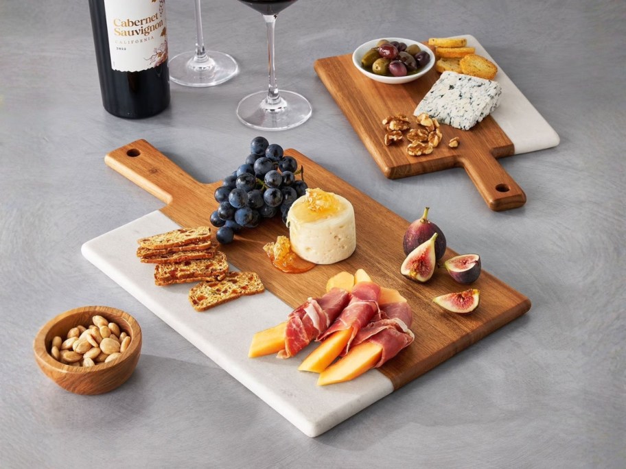 a set of wood and marble charcuterie boards with food on them