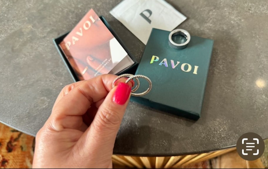 hand holding pavoi rings over jewelry box
