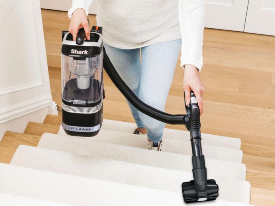 Woman using a Shark Navigator Lift-Away vacuum on stairs