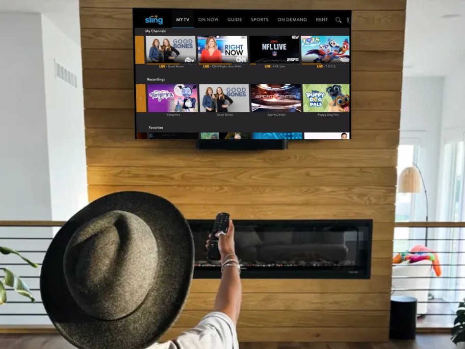 person watching a tv, pointing the remote towards it, Sling TV is on the screen
