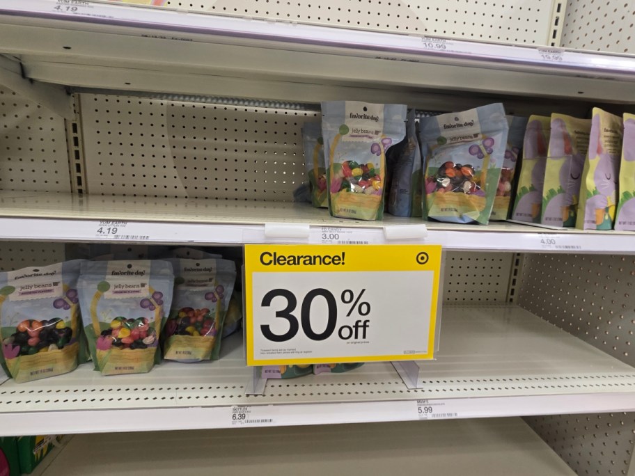 Bags of colorful jelly beans fill a store shelf with a prominent yellow sign announcing a 30% clearance sale.