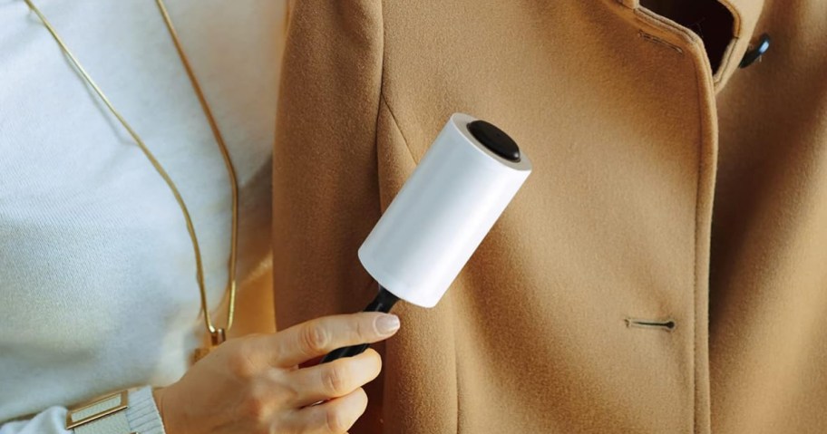 person using a lint roller on a coat