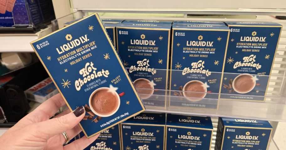 hand holding Liquid I.V. Hot Chocolate Sports Drink 1.9oz 6-Count in front of shelf of other boxes in store