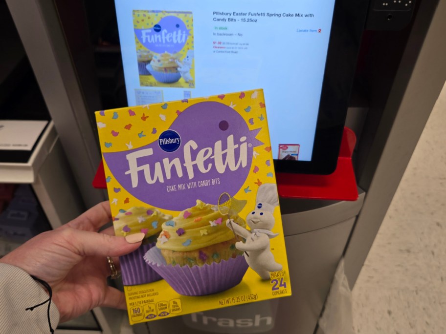 A hand holds a Pillsbury Funfetti cake mix box in front of a store checkout screen displaying the same product.
