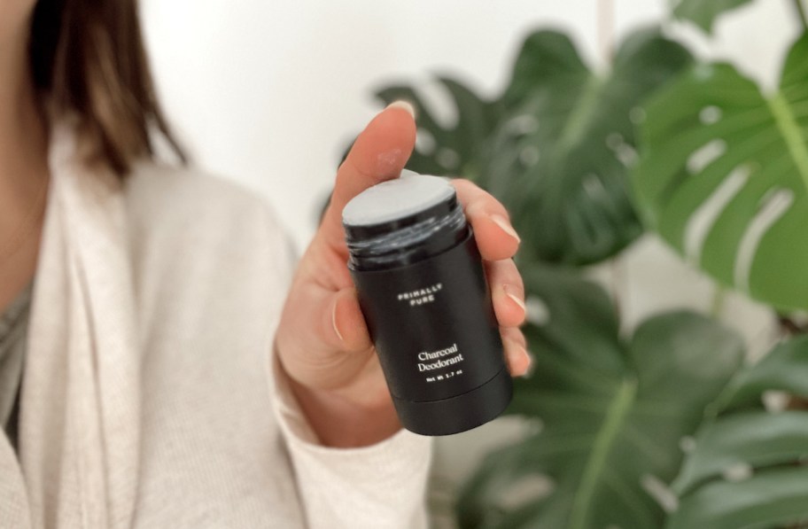hand holding primally pure charcoal deodorant without lid