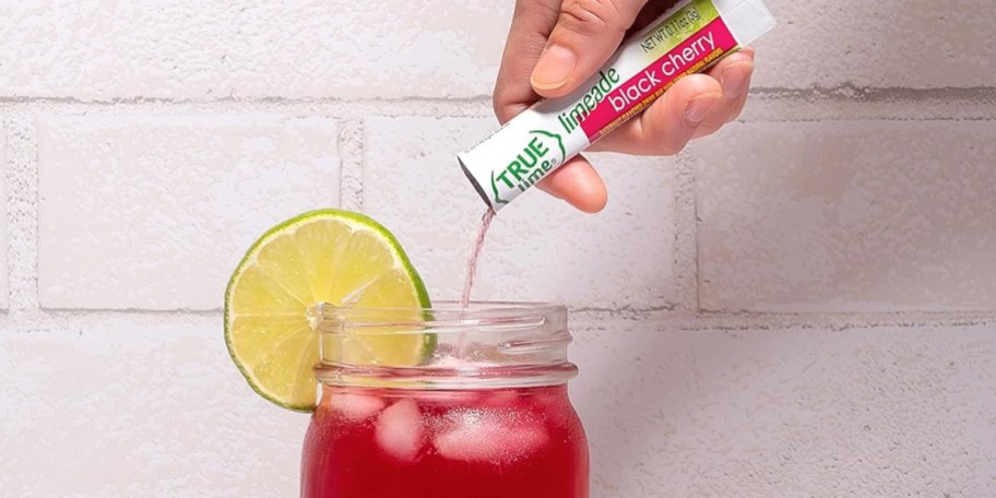 hand pouring tru lime packet into glass