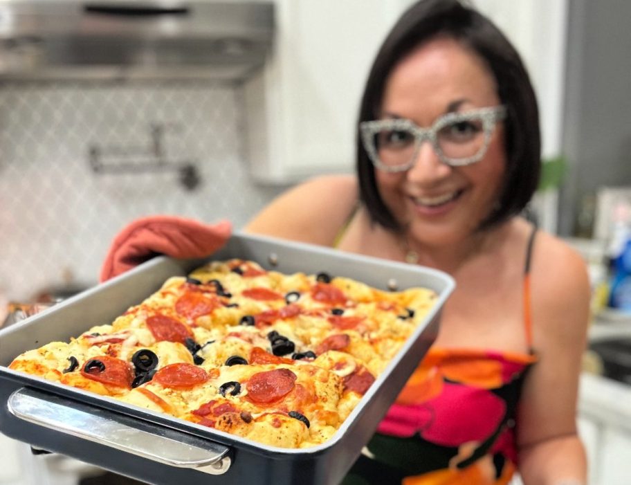 woman holding a tray of pizza focaccia bread