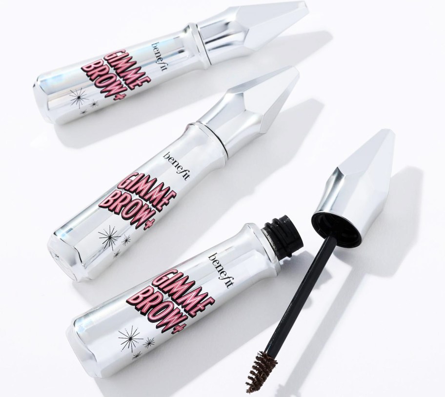 three silver tubes of Benefit Cosmetics Gimme Brow with one opened showing the wand