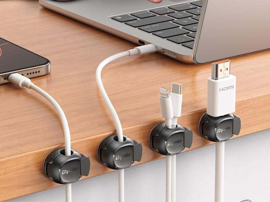 4 black magnetic cable clips holding chords on a desk with a computer