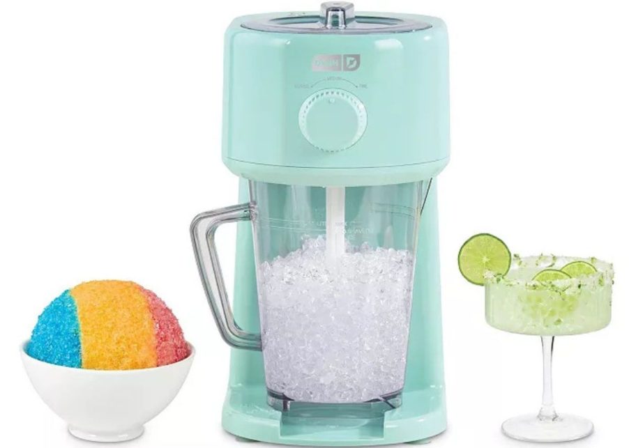 A slushy maker with shaved ice and a margarita next to it.