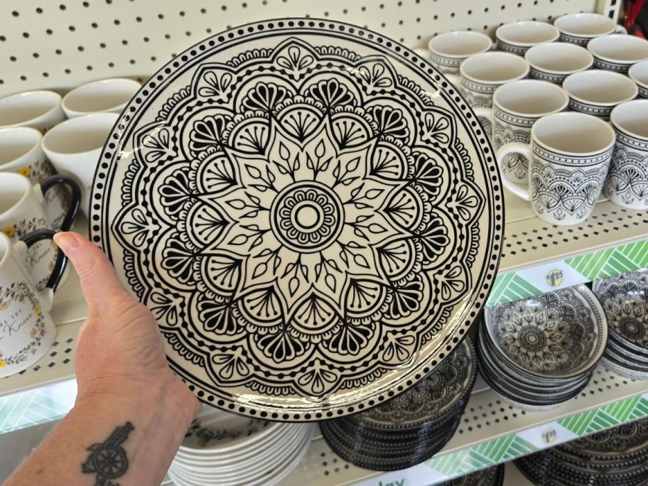 A person holding a black and white geometric patterned plate