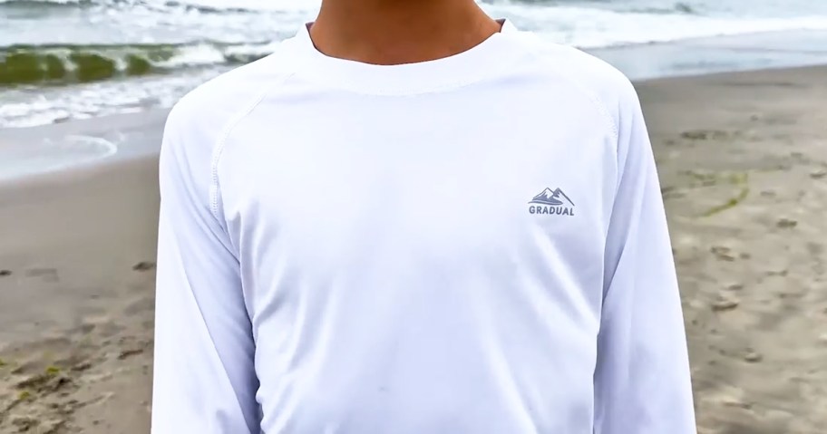 boy wearing a white rash guard shirt on the beach