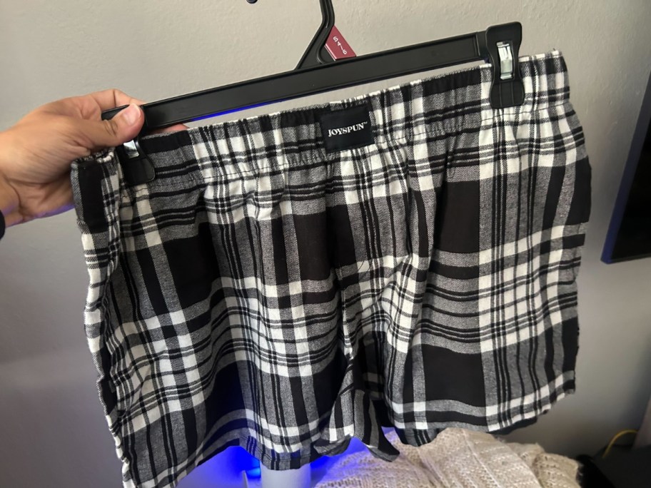 hand holding a pair of plaid boxer pajama shorts
