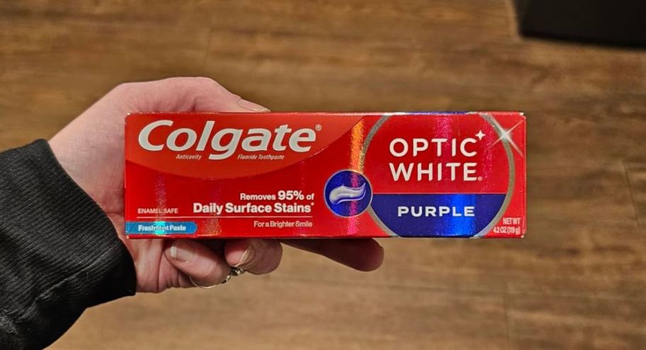 hand holding colgate optic white purple toothpaste in its package