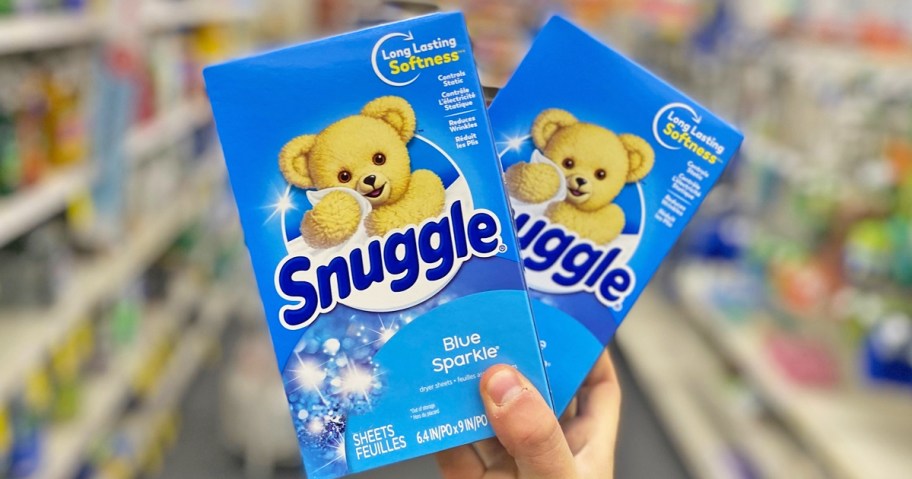 hand holding two blue boxes of Snuggle Dryer Sheets