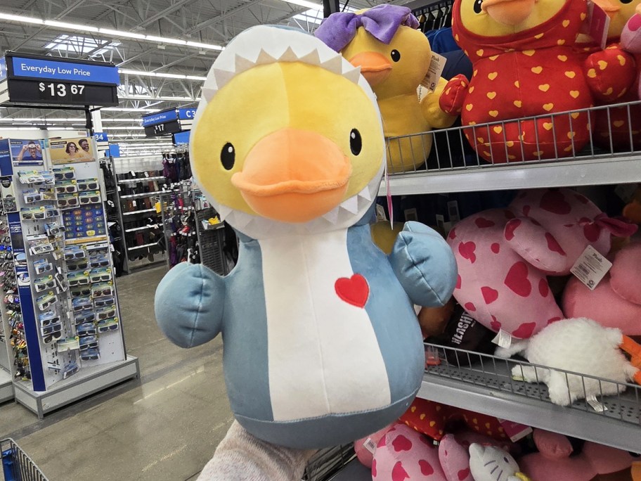 hand holding up a duck plush dressed in a shark outfit